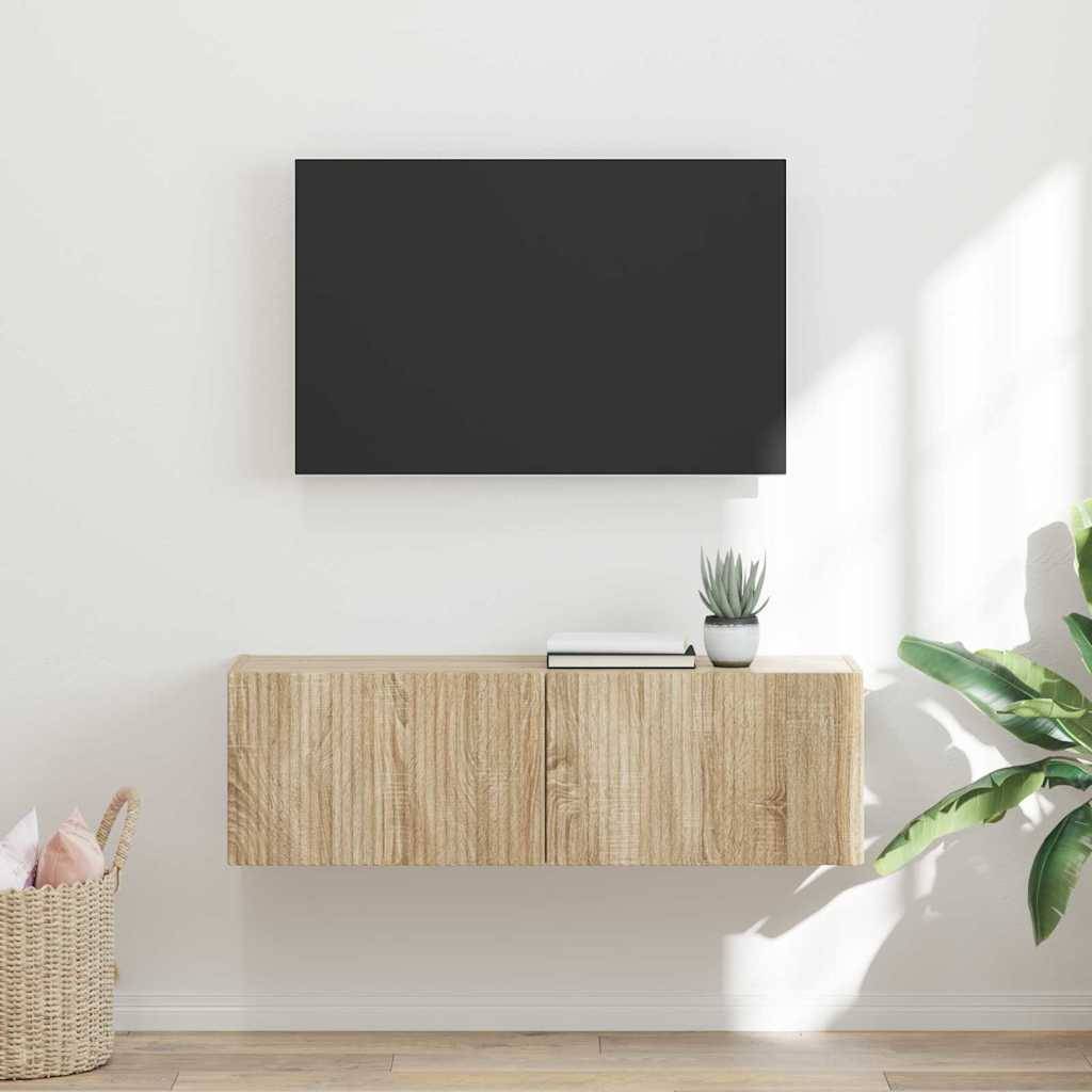 Ein minimalistisches Wohnzimmer mit einem schwebenden Holzschrank, einem an der Wand montierten Fernseher darüber und einer kleinen Pflanze neben einem geschlossenen Buch auf dem Schrank.