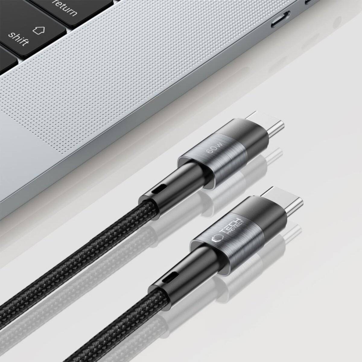 Nahaufnahme von zwei USB-C-Kabeln neben einer teilweise sichtbaren Laptop-Tastatur. Die Kabel verfügen über metallische Anschlüsse und geflochtene Kordeln.