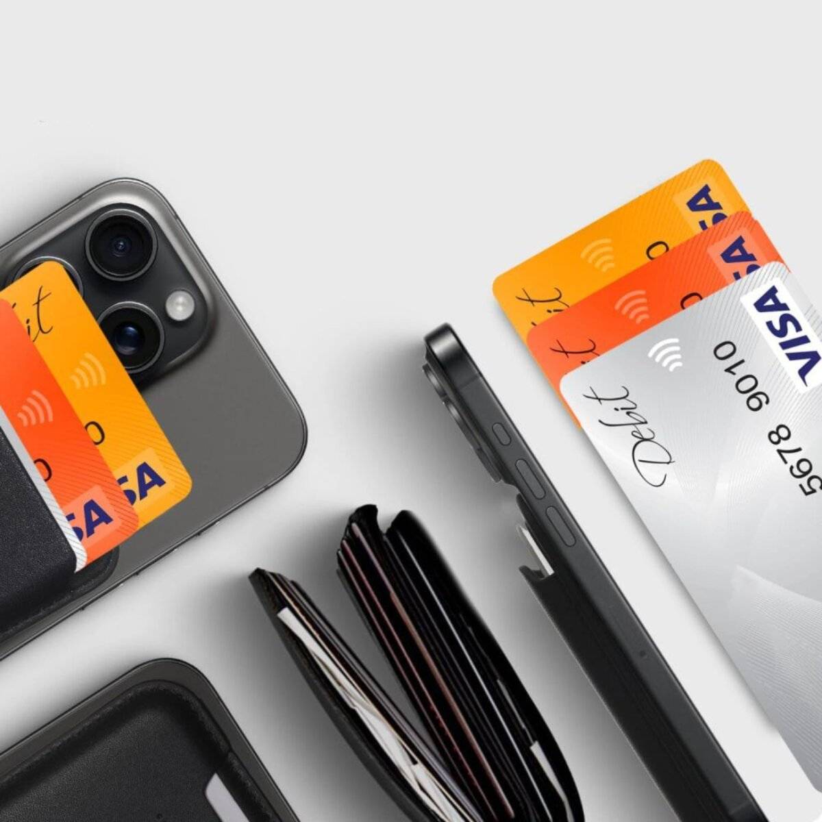 Ein Smartphone und Kreditkarten, darunter zwei orange Visa-Karten und eine weiße, die neben einem schwarzen offenen Portemonnaie auf einem hellen Hintergrund liegen.