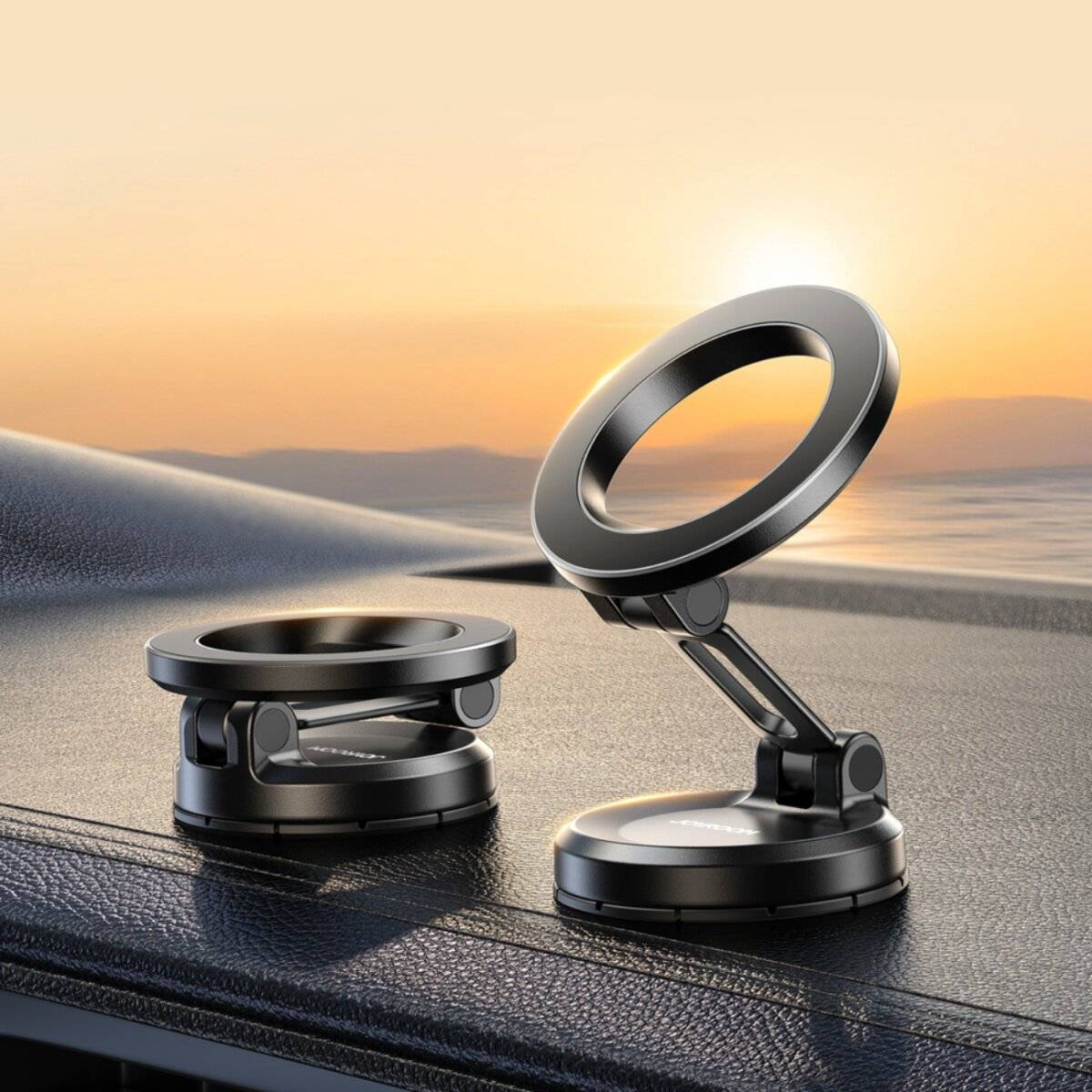 Zwei schwarze magnetische Telefonhalterungen auf einem Armaturenbrett eines Autos mit Sonnenuntergangsblick im Hintergrund, die ihr elegantes Design und ihre Verstellbarkeit präsentieren.