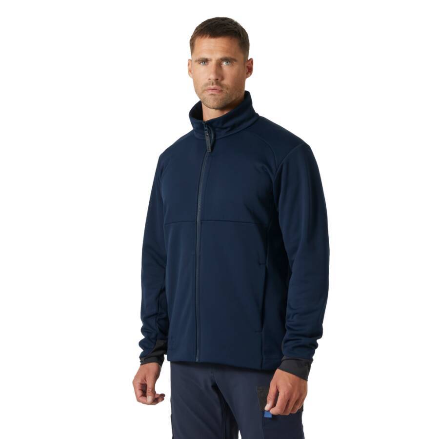 Ein Mann in einer marineblau-farbenen Reißverschlussjacke steht mit Blick nach vorne vor einem einfarbigen Hintergrund. Die Jacke hat einen hohen Kragen und lange Ärmel.