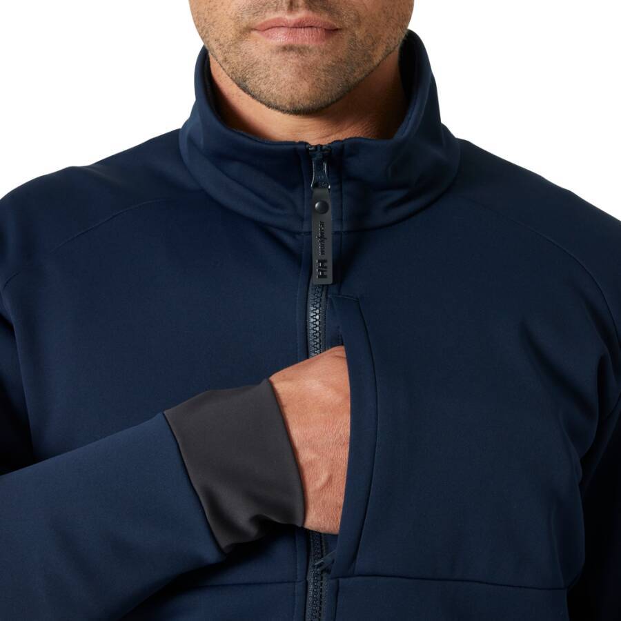 Eine Person, die eine marineblaue Jacke zuzippt und sich dabei auf den Oberkörper konzentriert. Die Jacke hat einen hohen Kragen und die Hand der Person ist dabei, den Reißverschluss zu justieren.