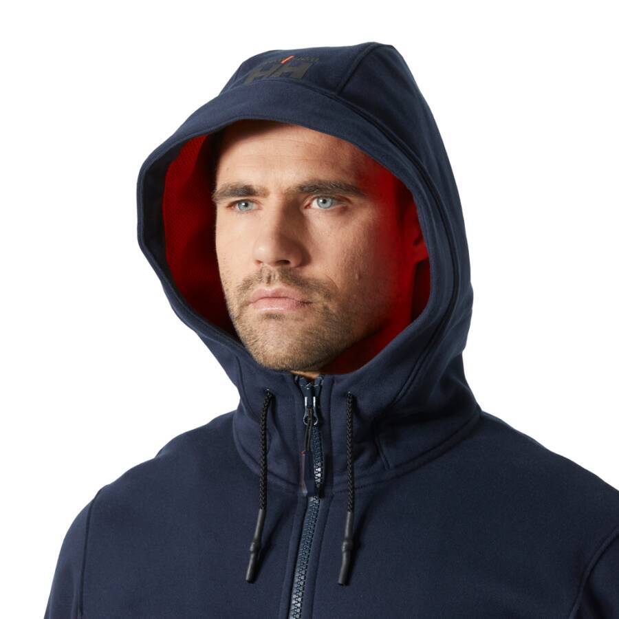 Eine Person, die einen marineblau-farbenen Hoodie mit rotem Innenfutter trägt, schaut mit neutralem Gesichtsausdruck geradeaus.