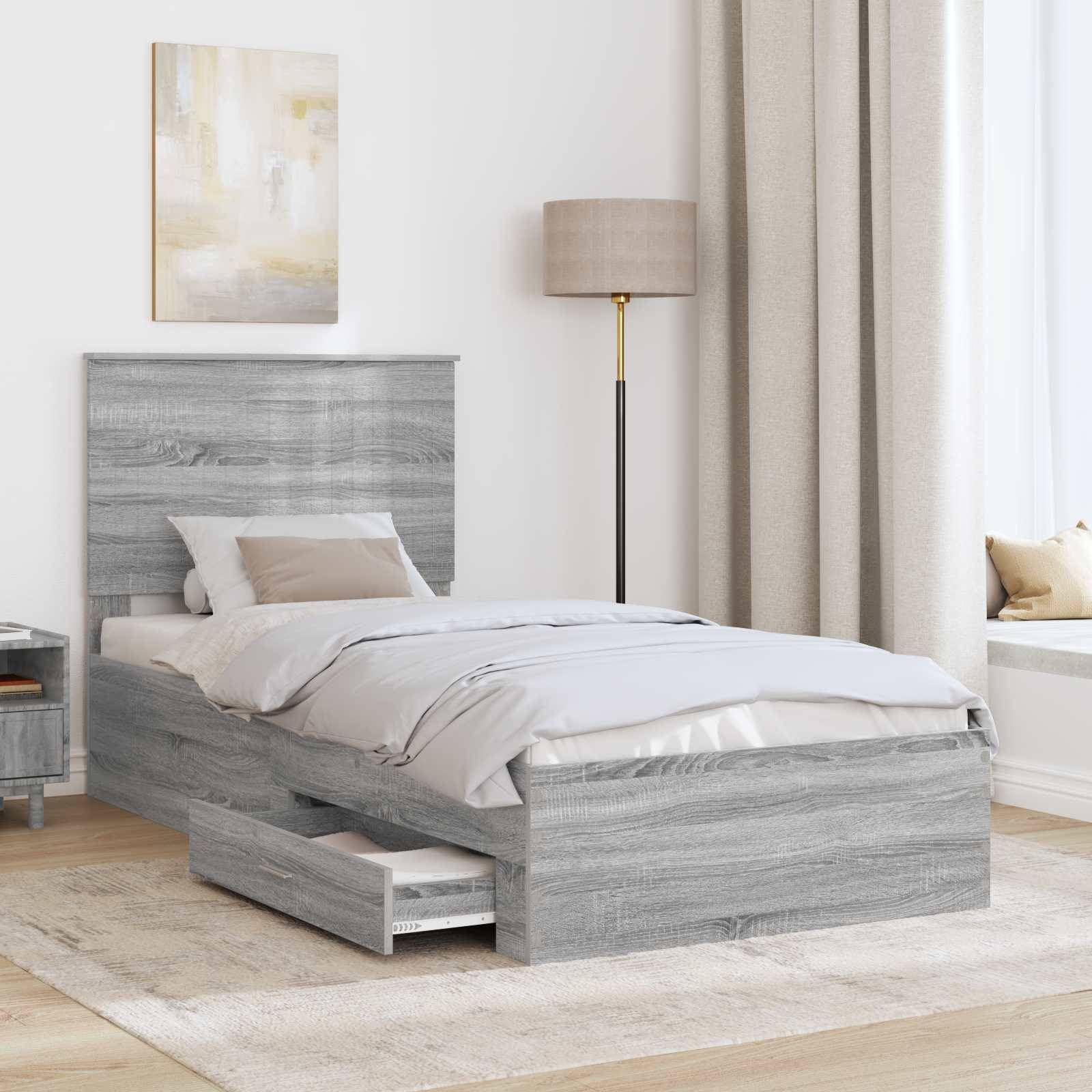 Ein graues Holzbett mit integrierten Schubladen zur Aufbewahrung, beige Bettwäsche, eine beige Lampe und ein kleiner Tisch in einem minimalistischen Schlafzimmer.