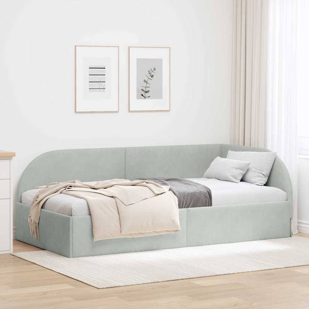 Ein minimalistisches Schlafzimmer mit einem hellgrauen Tagesbett, drapiert mit einer beige Wolldecke und Kissen, an einer hellgefärbten Wand mit zwei gerahmten Kunstwerken.