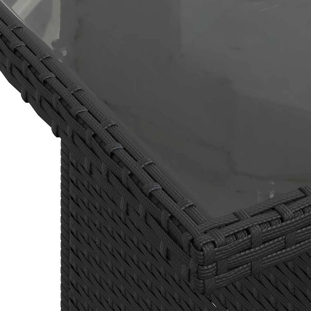 Nahaufnahme der Ecke eines dunklen, gewebten Outdoor-Tisches mit Glasplatte, die Textur und Konstruktion des Möbelstücks hervorhebt.