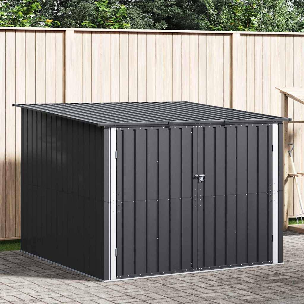 Eine kleine, dunkelgraue Metalllagerhütte mit einem spitzen Dach und einer verschlossenen Tür steht auf einer gepflasterten Terrasse, mit einem Holzzaun im Hintergrund.