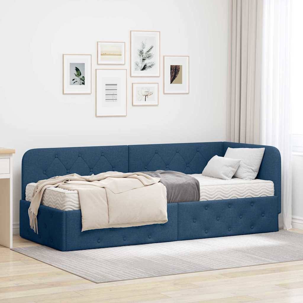 Ein blaugepolstertes Tagesbett mit einer Steppdecke und Kissen ist gegen eine beige Wand positioniert, über der Bilderrahmen mit Kunstwerken angebracht sind.