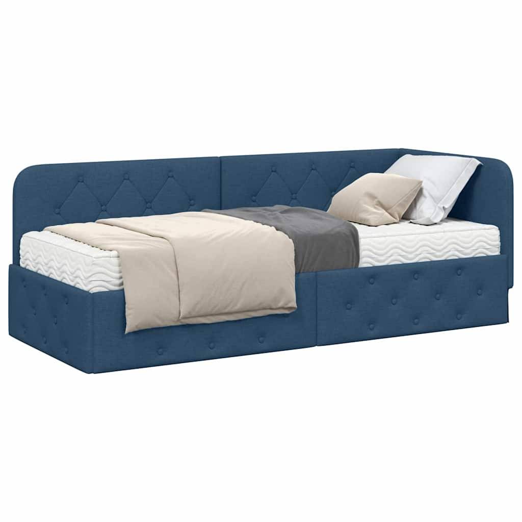 Ein blaupolstertes Tagesbett mit gestepptem Design, ausgestattet mit einer weißen Matratze und zwei Kissen, eines beige und eines weiß, mit einer beigen Decke.