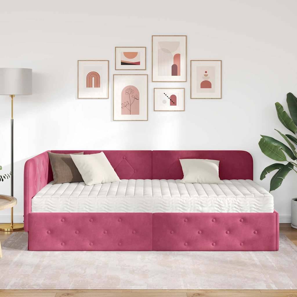 Ein modernes Wohnzimmer zeigt ein rosa gestepptes Tagesbett mit zwei Kissen, gerahmten Kunstwerken an der Wand, einer hohen Lampe und einer grünen Pflanze.