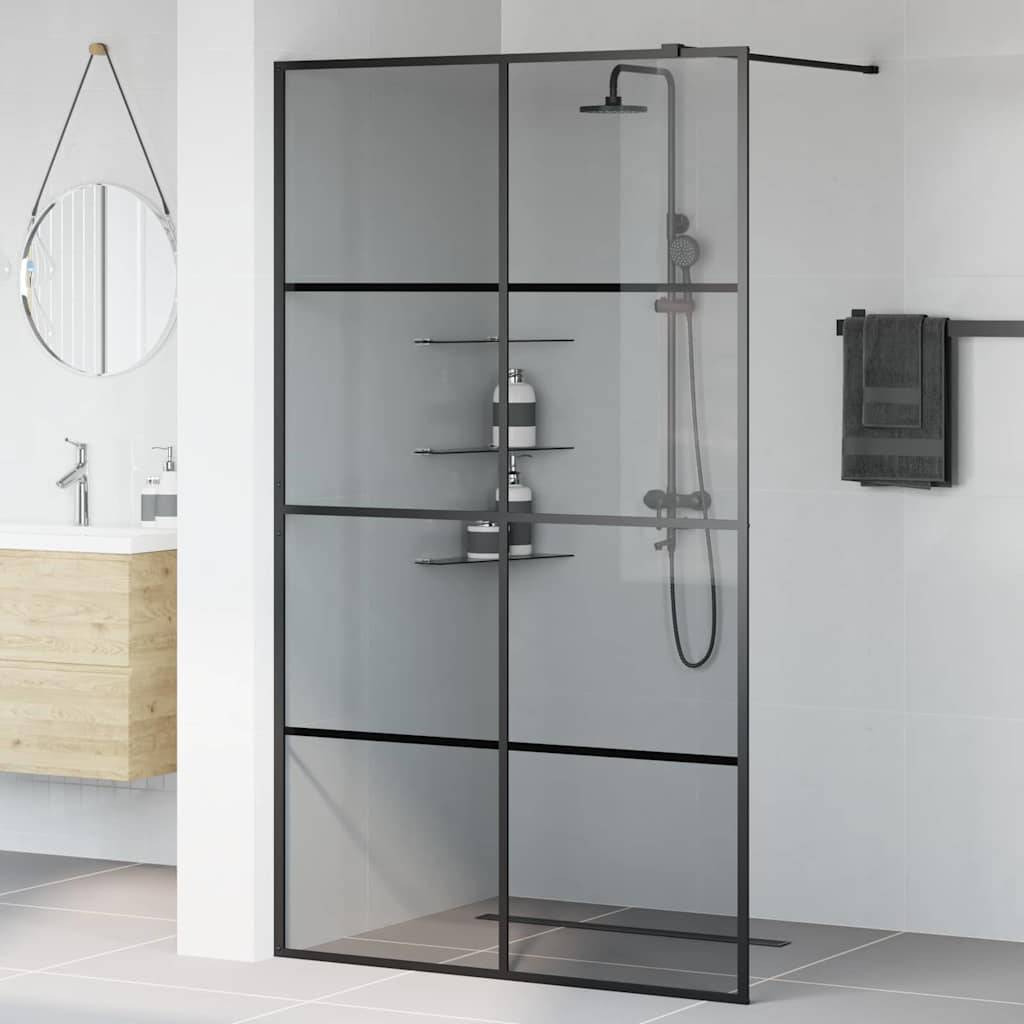 Modernes Badezimmer mit Glasduschkabine, schwarzem Metallrahmen und Regendusche. Wandmontiertes Waschbecken und runder Spiegel in der Nähe.