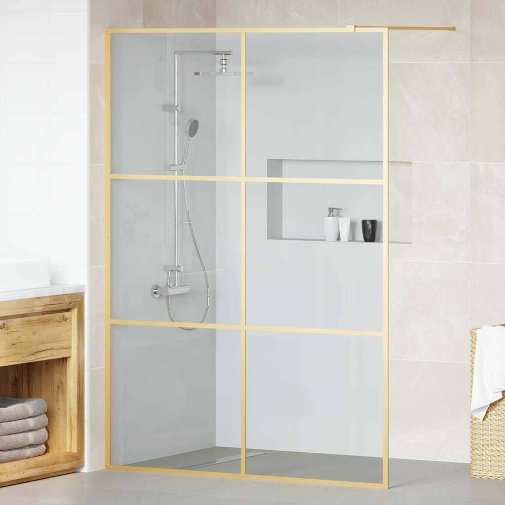 Modernes Badezimmer mit einer begehbaren Dusche, die eine Glasumrandung und goldene Verzierungen aufweist, einem Holzwaschbeckenunterschrank mit Handtüchern und beigen Fliesen.