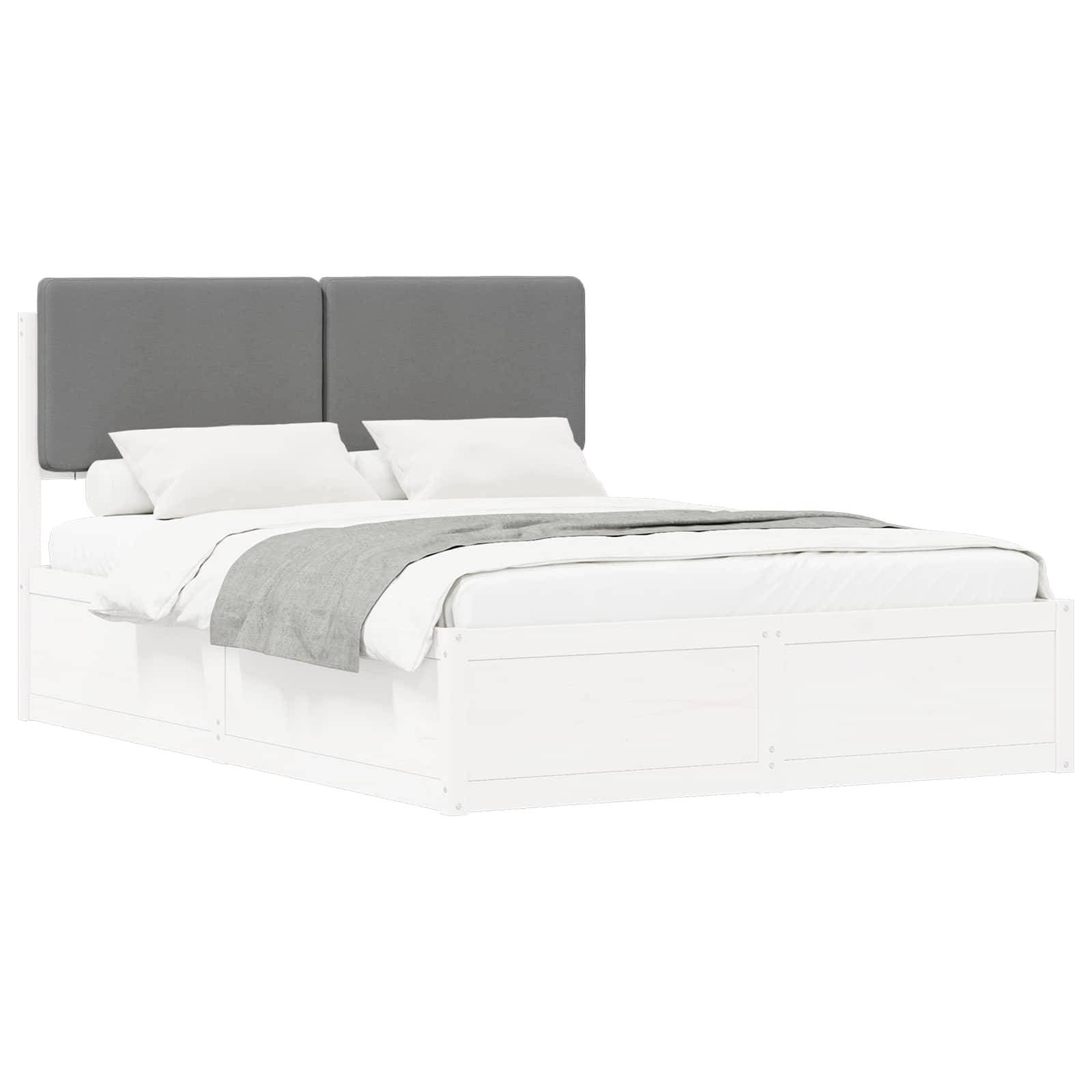 Ein modernes weißes Bett mit einem grauen Stoffkopfteil, ordentlich angeordneten weißen Kissen und einer grauen Decke, die das Bettlaken teilweise bedeckt.