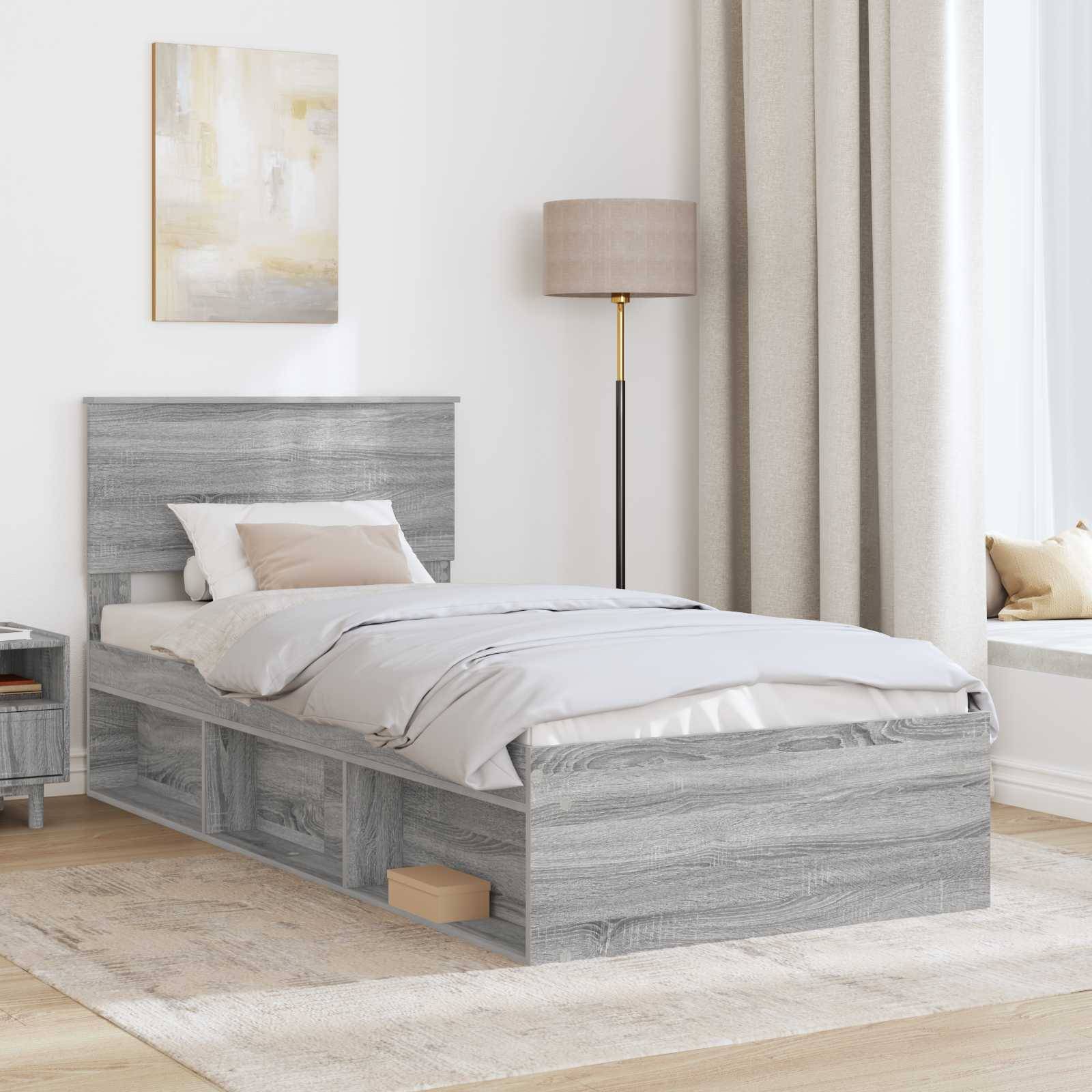 Ein modernes Schlafzimmer mit einem grauen Holzbett, weißer Bettwäsche, Nachttisch und Stehlampe. Ein Fenster mit Vorhängen und eine Sitzecke sind zu sehen.