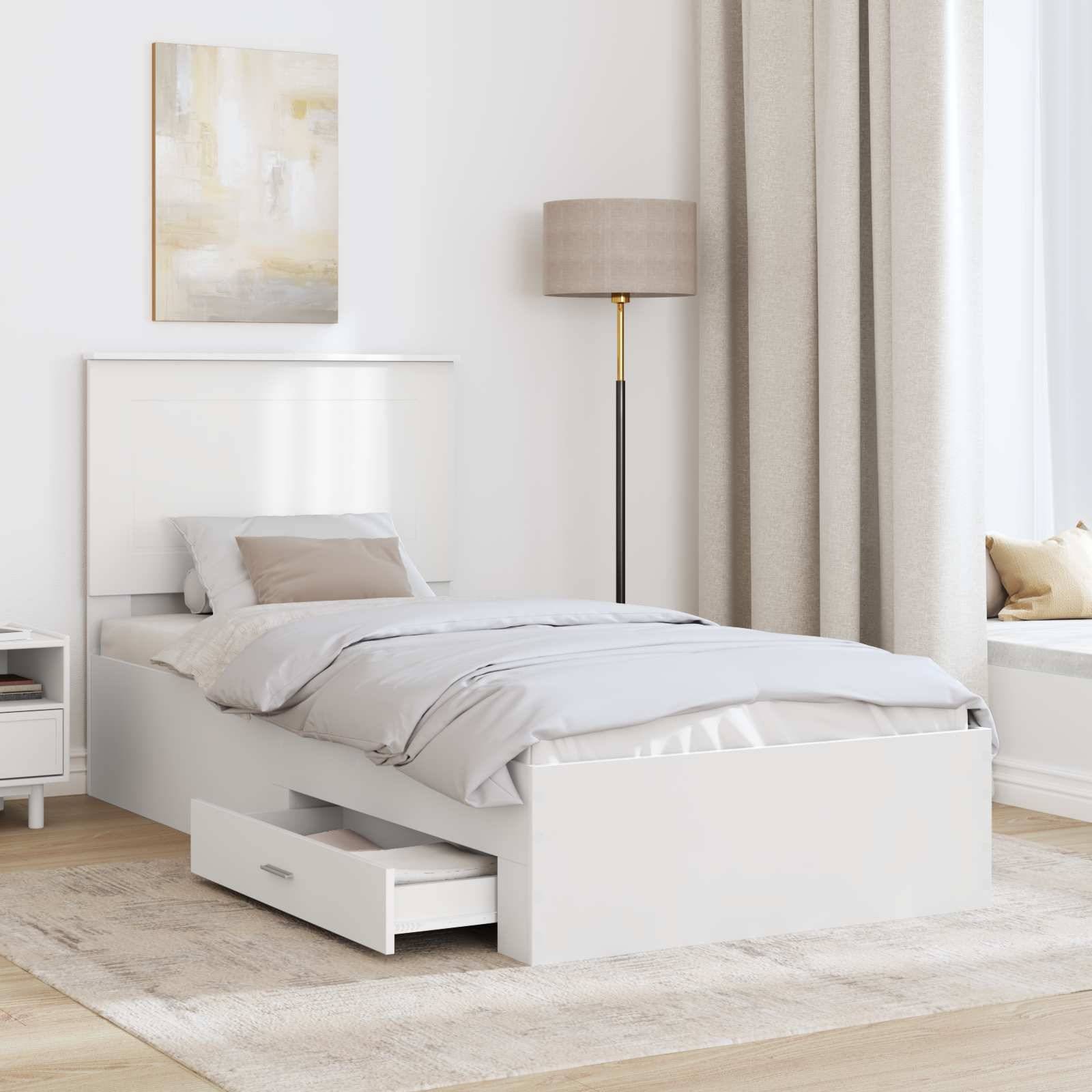 Ein minimalistisches Schlafzimmer mit einem weißen Bett mit beigem Bettzug, einer ausziehbaren Schublade, einer hohen Lampe und einem großen Fenster mit hellem Tageslicht.