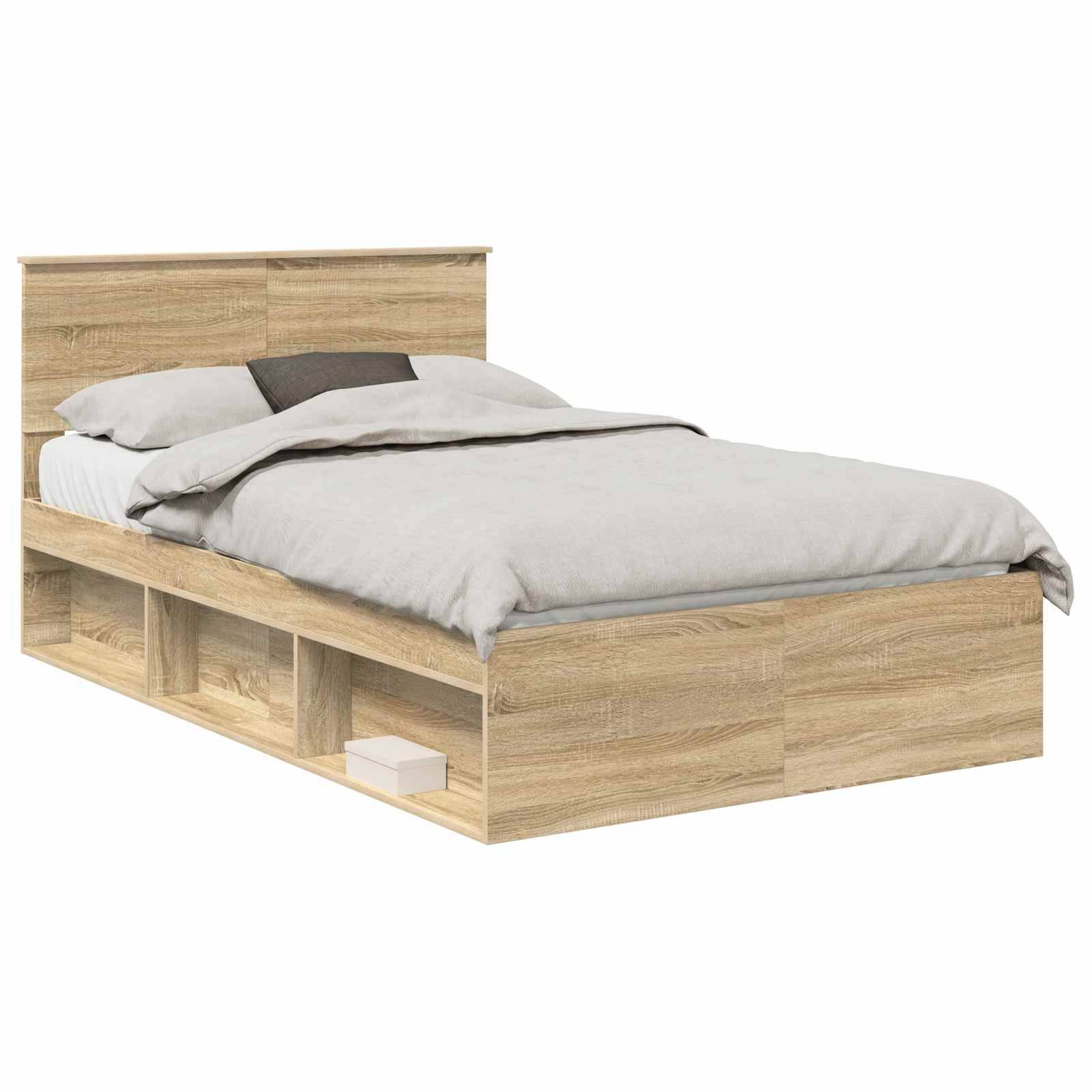 Ein Holzbettgestell mit integriertem Kopfteil und drei offenen Stauraumfächern darunter, auf dem ein Buch liegt. Das Bett ist mit einer hellgrauen Decke und Kissen bezogen.