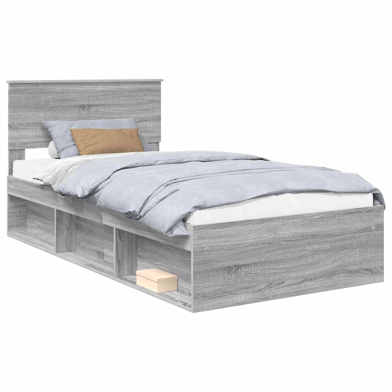 Ein graues Bett mit einem Holzrahmen, das an der Basis integrierte offene Ablagerungsregale und ein passendes Kopfteil aufweist. Es ist mit hellblauer Bettwäsche und zwei Kissen, einem grauen und einem braunen, bezogen.