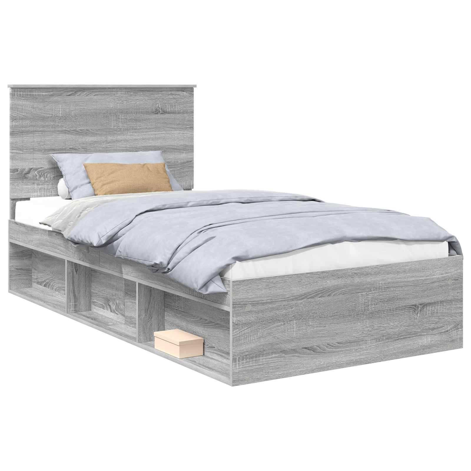 Ein einzelnes graues Holzbett mit Kopfteil, blau-grauer Bettwäsche, zwei Kissen und integrierten Ablageregalen an den Seiten und am Fußende.