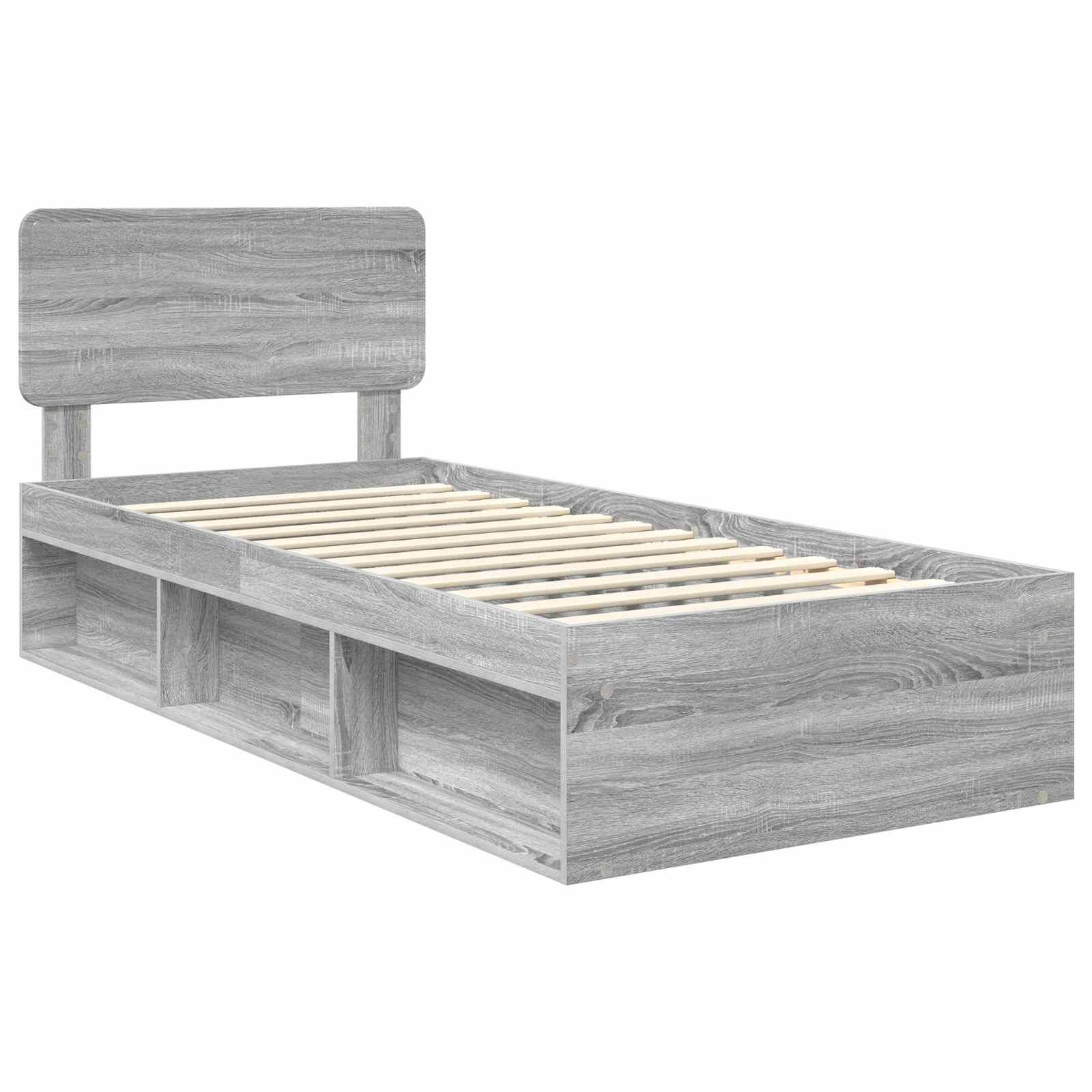 Ein grauer Holz-Zwillingsbettrahmen mit einem schlichten Kopfteil und drei offenen Stauraumbereichen unterhalb der Basis.