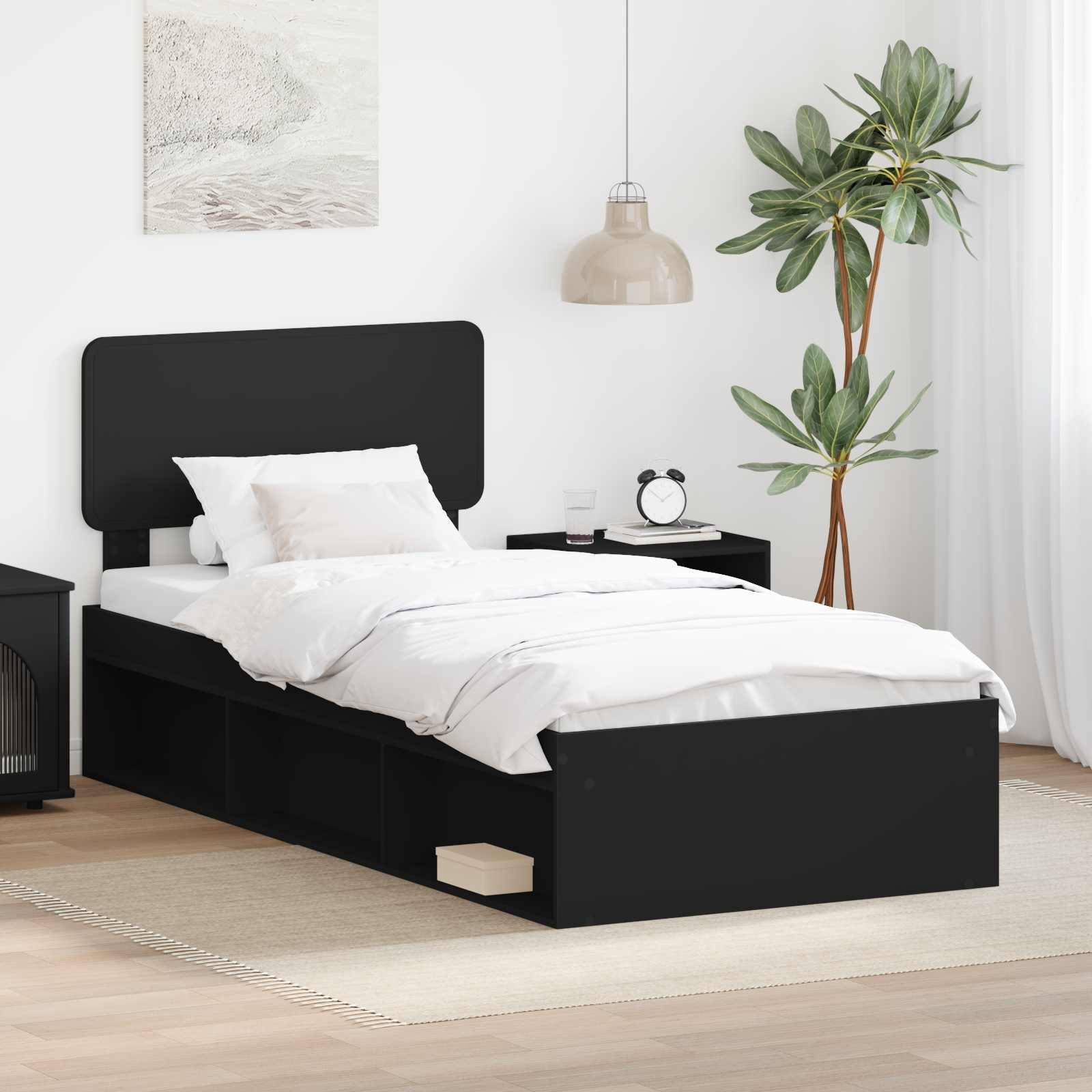 Modernes Schlafzimmer mit einem schwarzen Bett mit Aufbewahrungsschubladen, weißer Bettwäsche, Nachttischen mit Lampen und einer Topfpflanze in der Ecke.