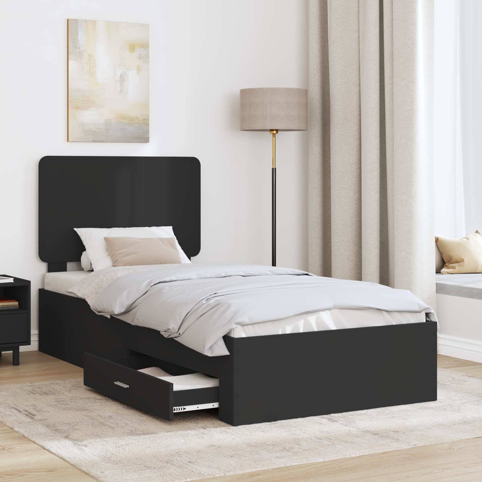 Ein modernes Schlafzimmer mit einem dunklen Bett, das unter sich eine offene Schublade mit Stauraum aufweist. Eine Lampe und gerahmte Kunstwerke befinden sich im Hintergrund; Sonnenlicht fällt herein.