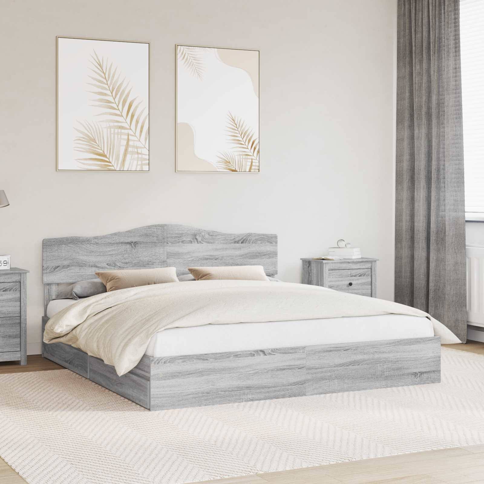 Schlafzimmer mit grauem Holzbett, cremefarbener Bettwäsche, zwei Kunstdrucken darüber, Nachttischen und einem Vorhang. Neutrale, moderne Einrichtung.