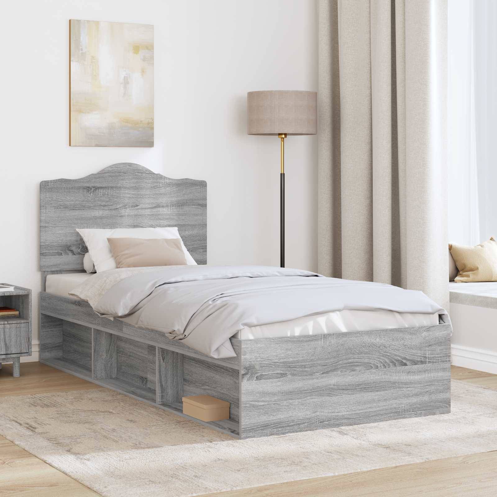 Ein modernes Schlafzimmer mit einem grauen Holzbett mit Aufbewahrungsschubladen, weißer und beige Bettwäsche, einem Nachttisch, einer Lampe, einem großen Fenster und Kunstwerken.