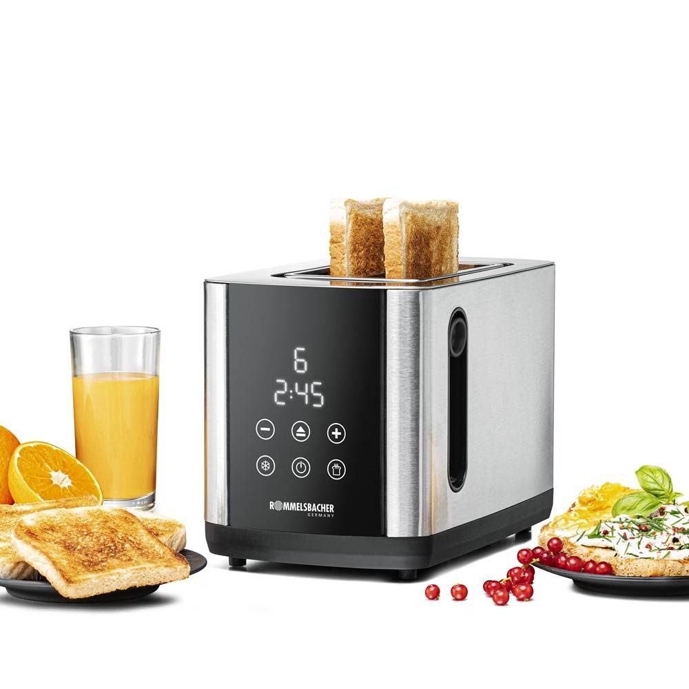 Ein Toaster aus Edelstahl mit digitaler Anzeige, der zwei Scheiben Brot röstet. In der Nähe stehen ein Glas Saft, Toast mit Butter und Obst.