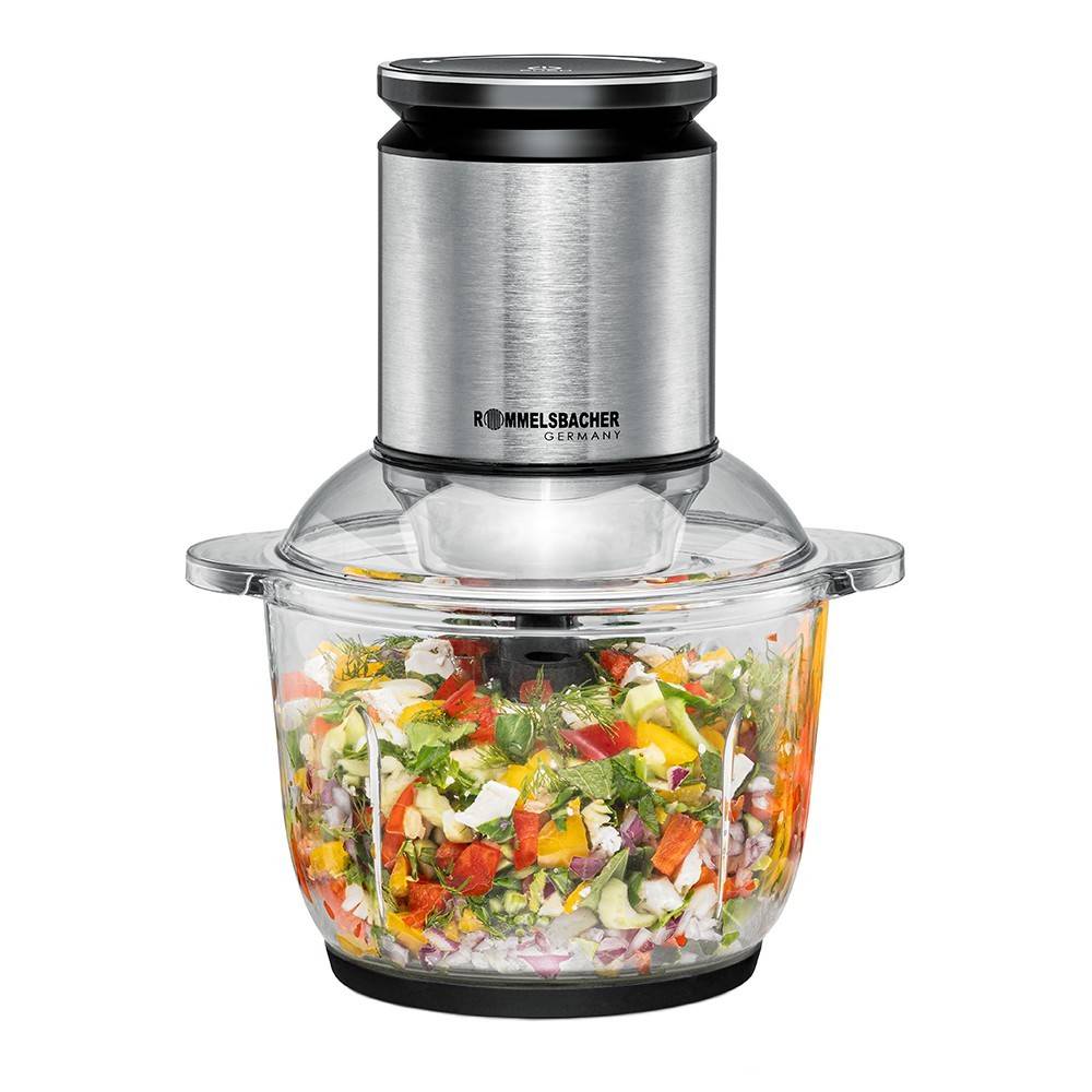 Eine Küchenmaschine aus Edelstahl, die verschiedene kleingeschnittene Gemüsesorten wie Tomaten, Gurken und Paprika in einer Glasschüssel püriert.