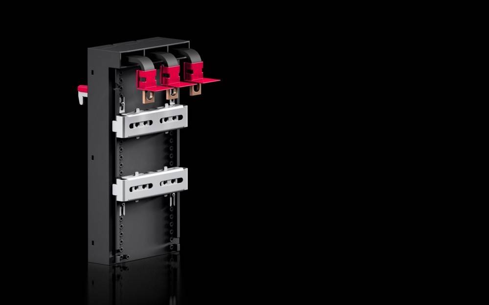 Ein schwarzes elektrisches Gerät mit drei roten Hebeln und einem grauen Panel auf schwarzem Hintergrund, das industrielle Designelemente präsentiert.