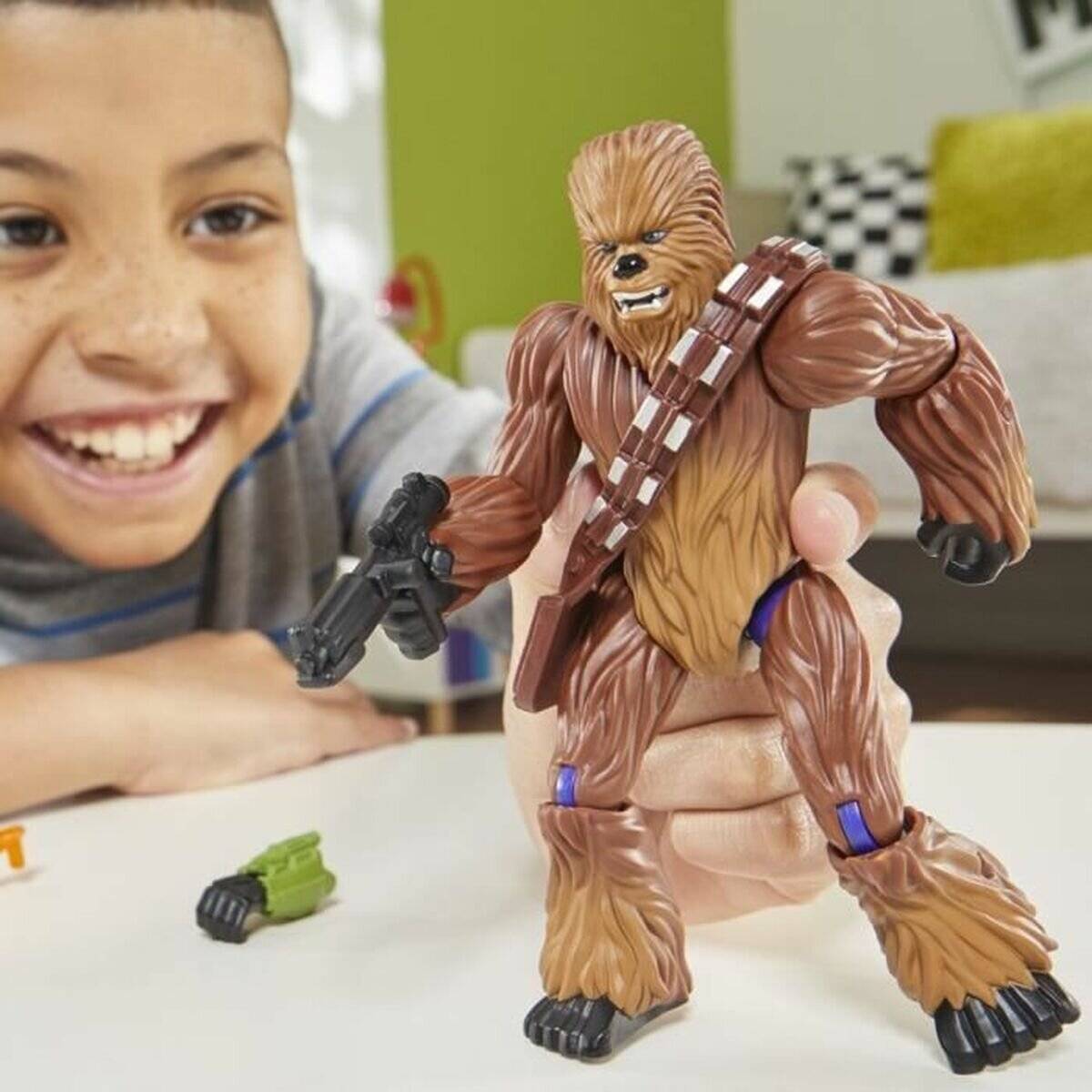 Ein Kind lächelt, während es mit einer Actionfigur einer braunen, haarigen Figur spielt, die eine schwarze Waffe hält. Die Umgebung ist farbenfroh und verspielt.