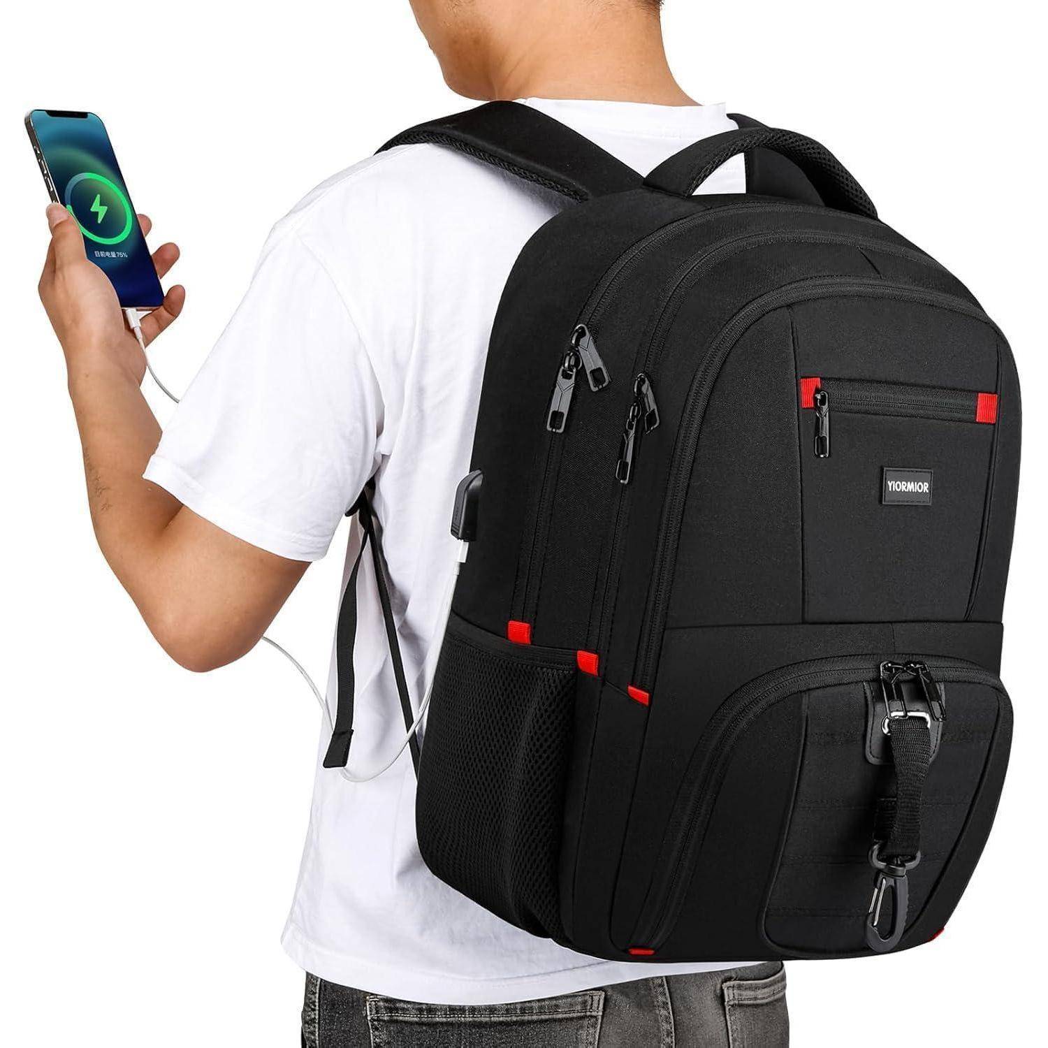 Eine Person trägt einen schwarzen Rucksack und lädt ein Handy mit einem sichtbaren USB-Kabel. Der Rucksack verfügt über mehrere Fächer und rote Akzente.