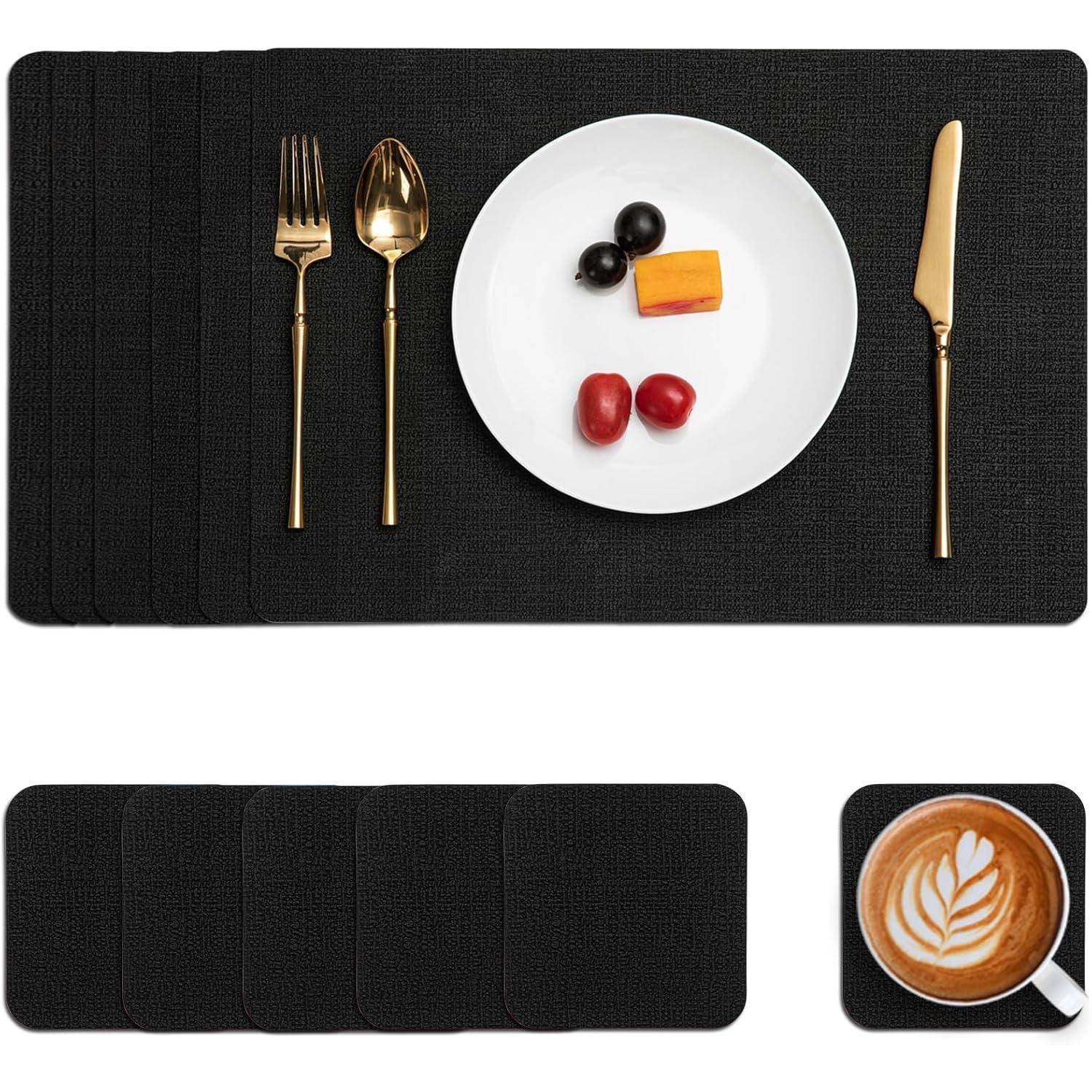 Eine formelle Gedeckung auf einem schwarzen Platzdeckchen mit einer Gabel, einem Löffel, einem Messer und einem weißen Teller mit Käse, Oliven und Tomaten; ein Latte-Art-Kaffee daneben.