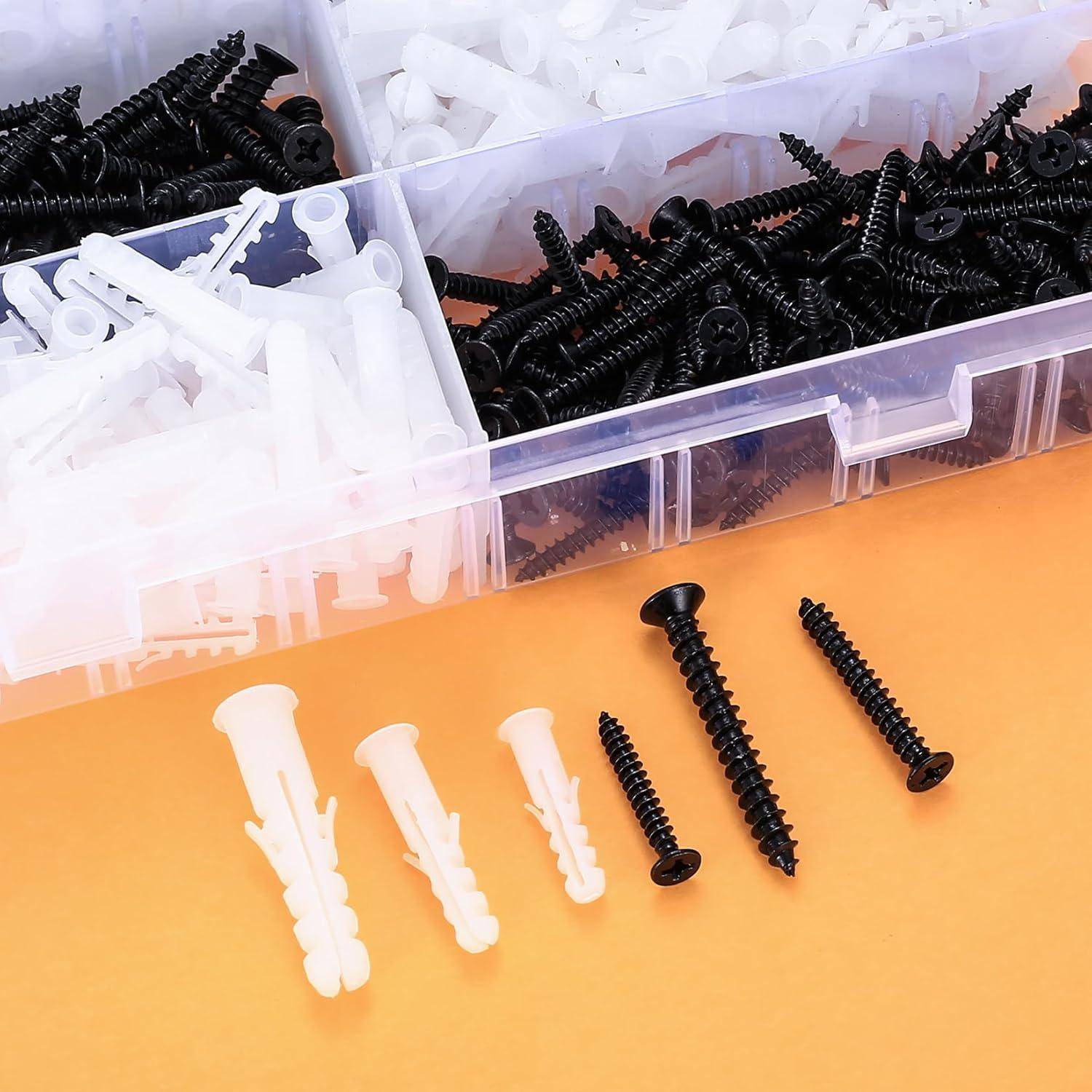 Verschiedene schwarze und weiße Schrauben und Dübel sind auf einer Oberfläche angeordnet, mit Aufbewahrungsboxen im Hintergrund.