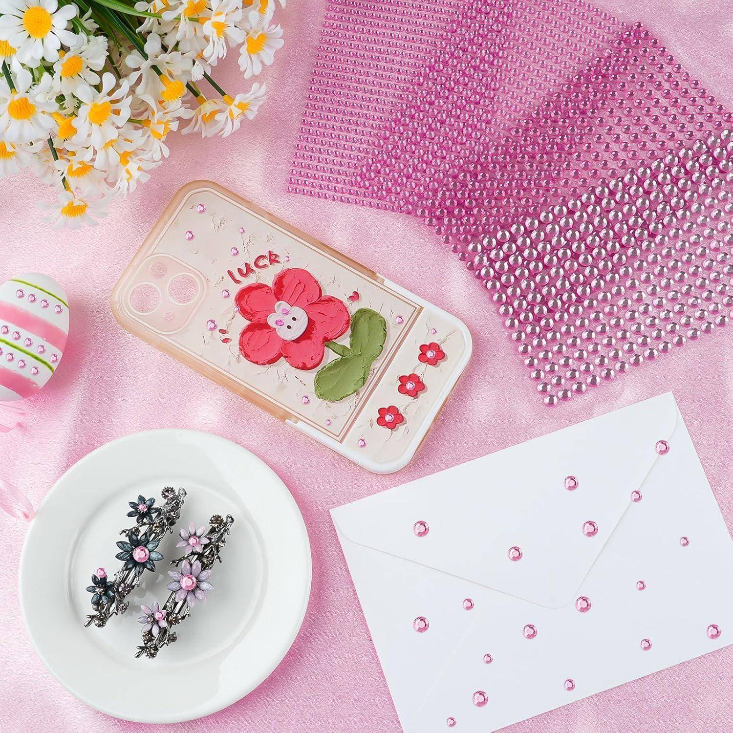 Ein Flat-Lay-Bild mit dekorativen Gegenständen: eine Handyhülle mit pinker Blumendesign, ein Teller mit floralen Haarspangen, einem Umschlag und pinken Mustern neben einem Gänseblümchen-Strauß.