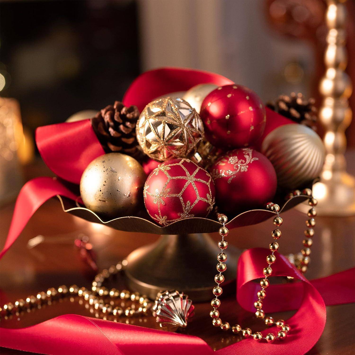 Eine festliche Anordnung aus roten und goldenen Weihnachtskugeln mit Tannenzapfen in einer Schale, akzentuiert durch ein rotes Band und eine goldene Perlengirlande.