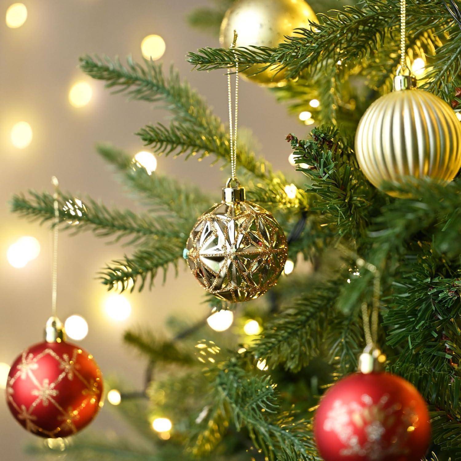 Weihnachtsbaumzweige geschmückt mit goldenen und roten Christbaumkugeln. Weich fokussierte Lichter erzeugen eine warme, festliche Atmosphäre.