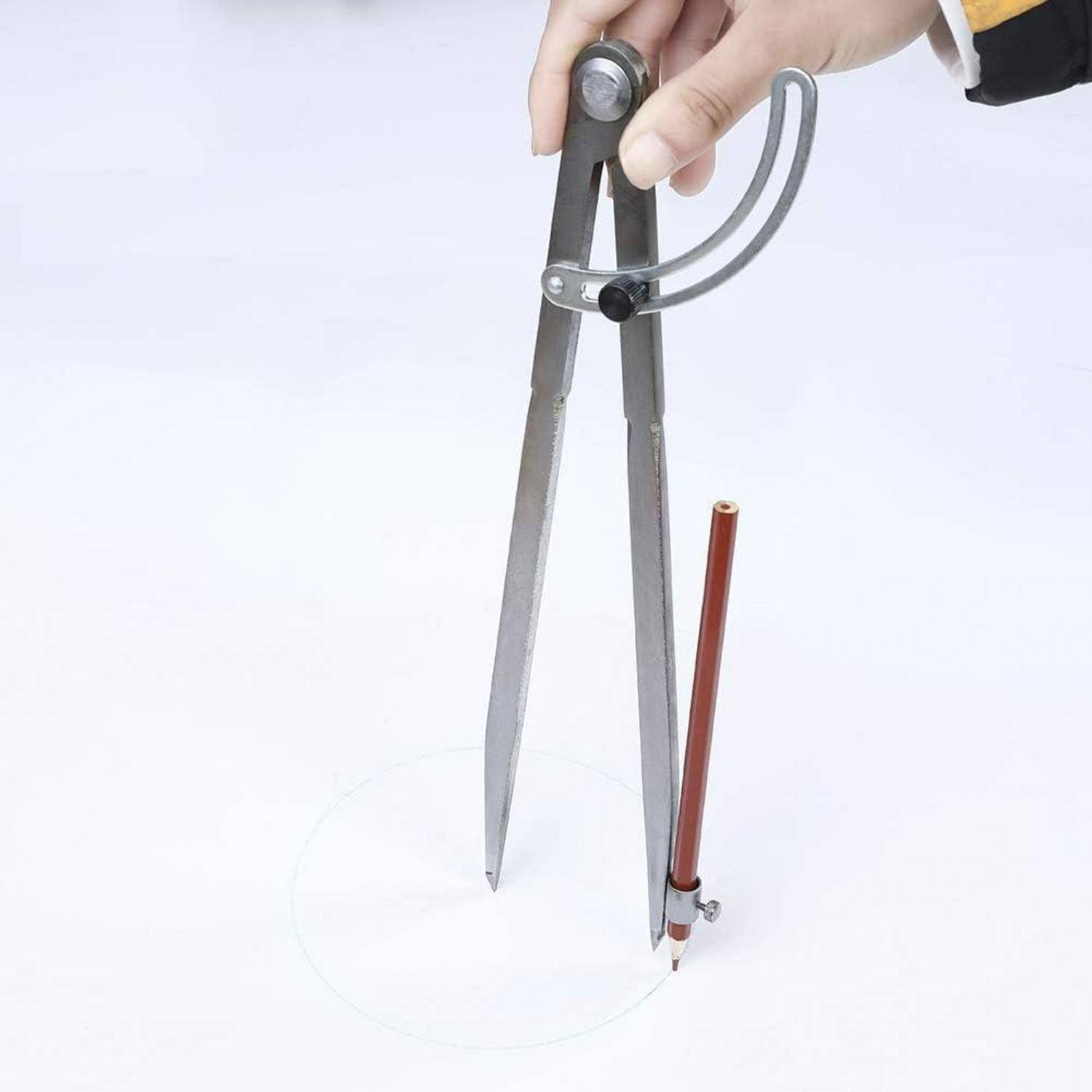 Eine Hand, die einen Metallzirkel verwendet, um einen Kreis auf weißem Hintergrund zu zeichnen und zeigt, wie das Werkzeug für geometrische Zwecke eingesetzt wird.