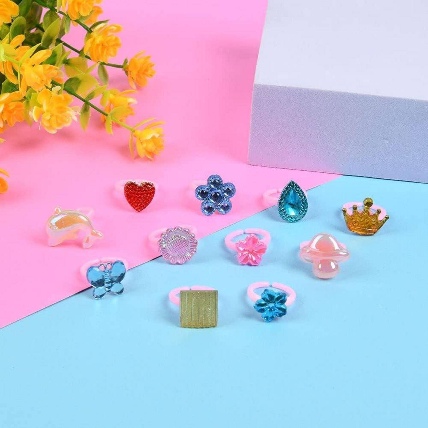 Verschiedene bunte Spielzeug-Ringe, die auf einem rosa und blauen Hintergrund angeordnet sind, mit gelben Blumen auf der linken Seite.