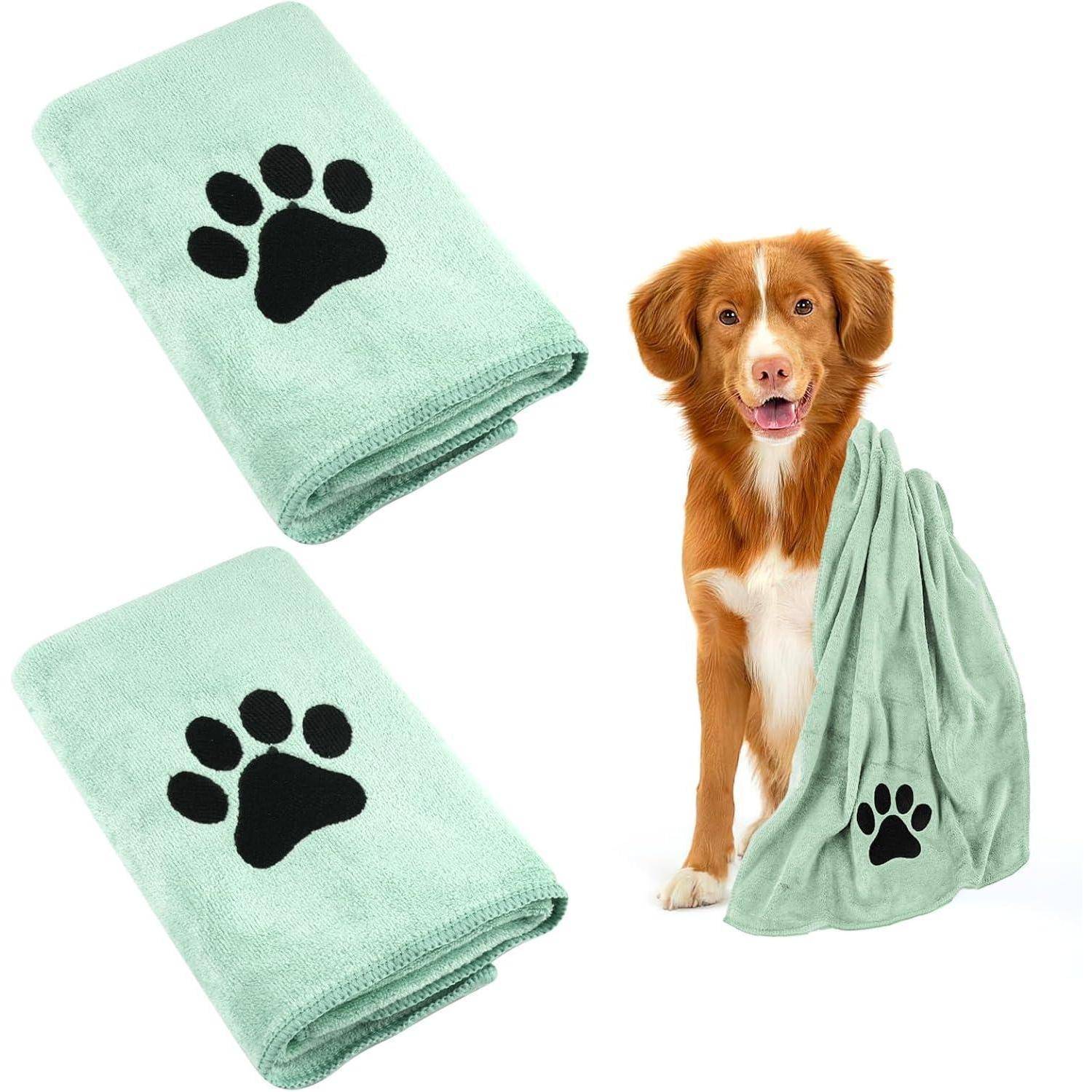 Ein Hund mit weißer Brust sitzt neben einem grünen Handtuch mit einem schwarzen Pfotenabdruck. Derselbe Handtuch ist zweimal gefaltet und erscheint links.