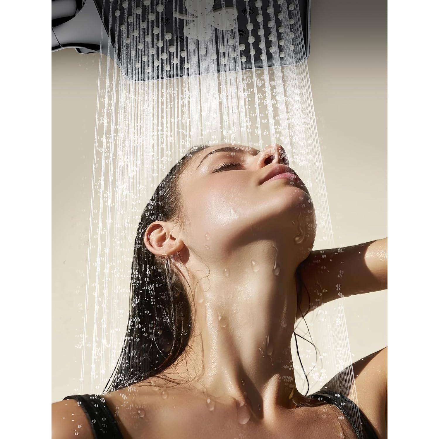 Eine Person genießt eine erfrischende Dusche unter einem quadratischen Duschkopf, wobei das Wasser herabfließt und das Sonnenlicht ihre nasse Haut hervorhebt.