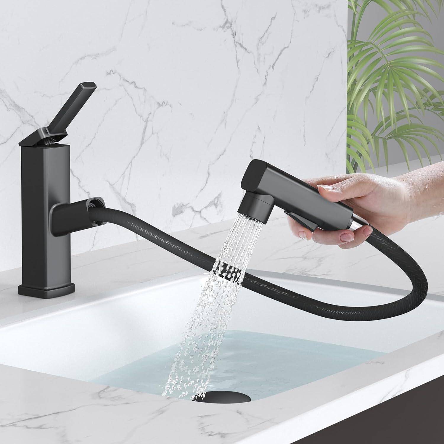 Eine Hand demonstriert die Verwendung einer flexiblen ausziehbaren Küchenarmatur, die Wasser in ein weißes Waschbecken spritzt, wobei sich im Hintergrund eine Marmorarbeitsplatte befindet.