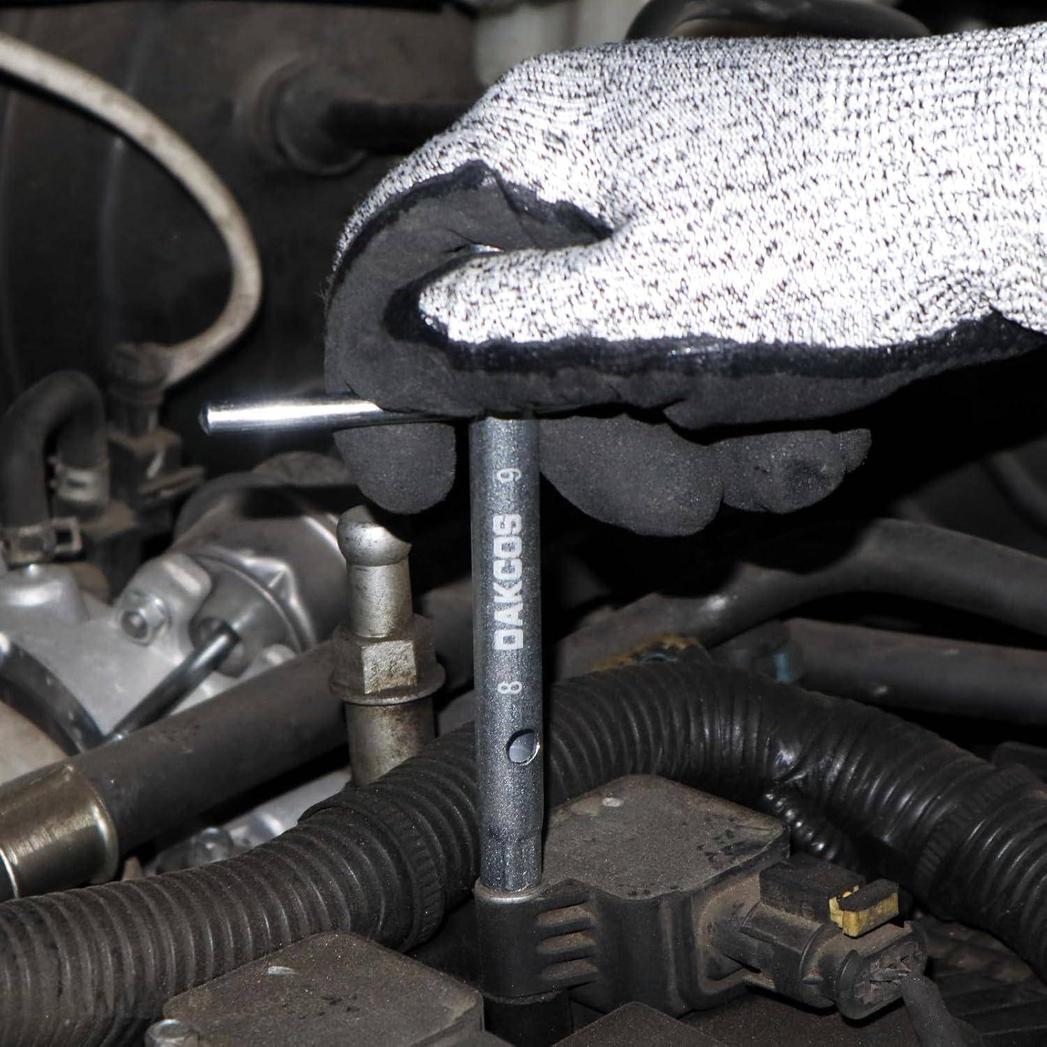 Eine Handschuh tragende Hand benutzt einen Steckschlüssel, um eine Komponente des Automotors festzuziehen und zeigt damit automotive Wartungsarbeiten.