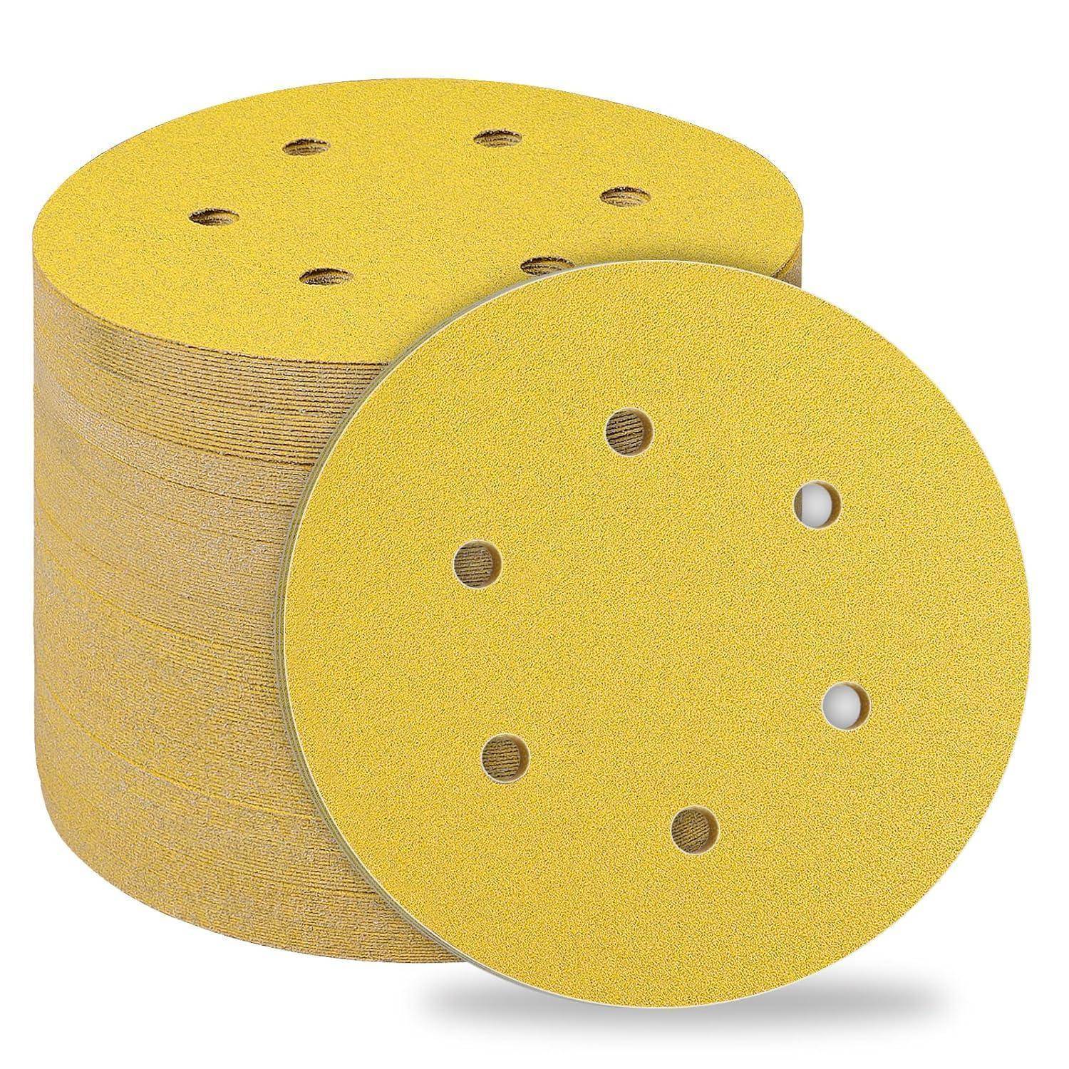 Ein Stapel gelber runder Schleifpapierscheiben mit Löchern, die zum Schleifen von Oberflächen verwendet werden und dabei das Schleifmaterial und die Perforationen hervorheben.