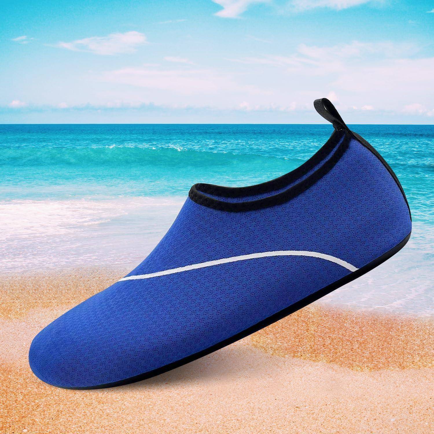 Ein blauer Wasserschuh mit schwarzem Rand wird auf einem sandigen Strand gezeigt, mit einem klaren blauen Himmel und Ozean im Hintergrund.