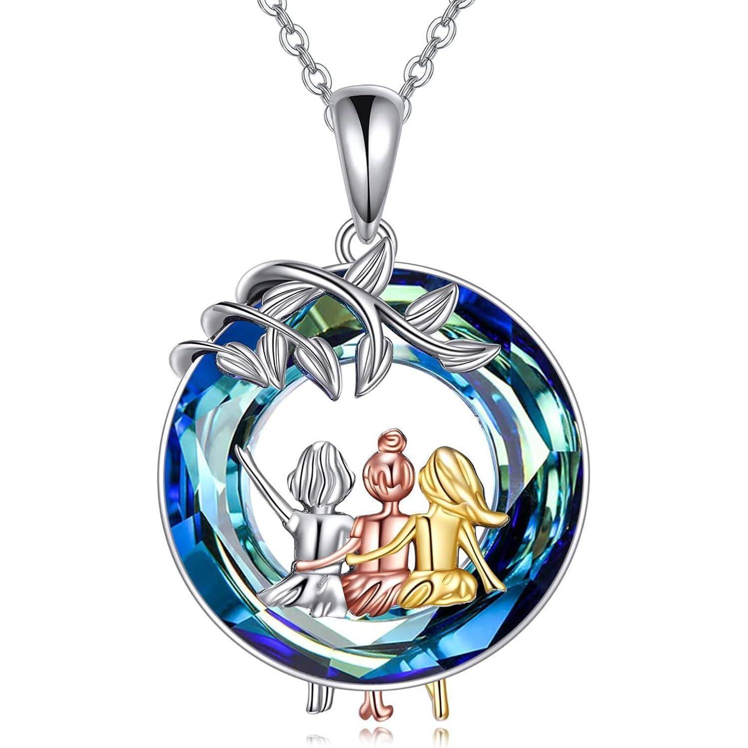 Eine kreisförmige Anhänger mit einem Kristalldesign zeigt drei Figuren, die gemeinsam sitzen und Freundschaft symbolisieren. Die Figuren sind in Silber, Roségold und Gold gefärbt.
