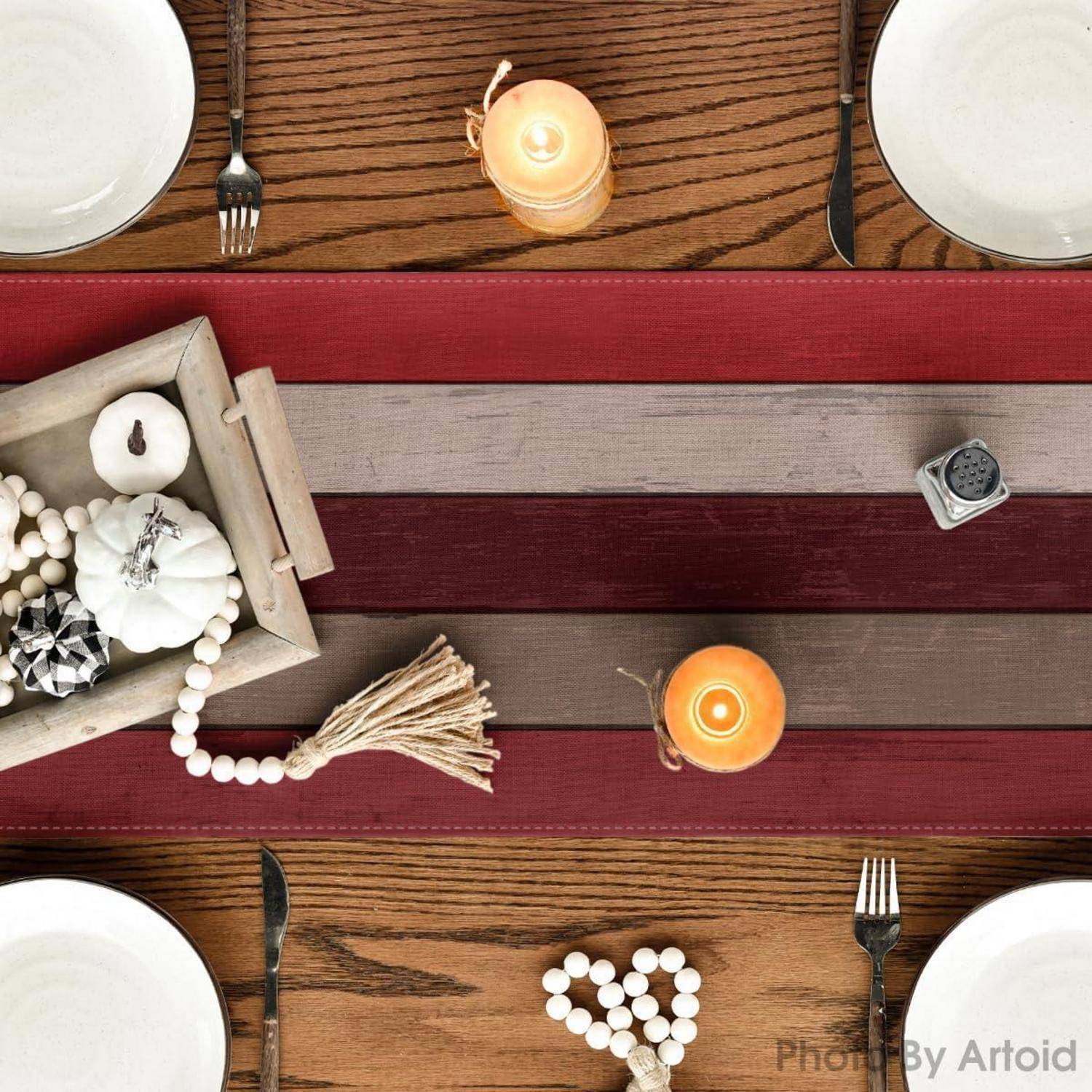 Ein Holztisch, gedeckt für eine Mahlzeit mit Tellern, Gabeln, Kerzen und dekorativen Elementen, darunter Perlen und ein kleines Tablett mit Kürbissen.