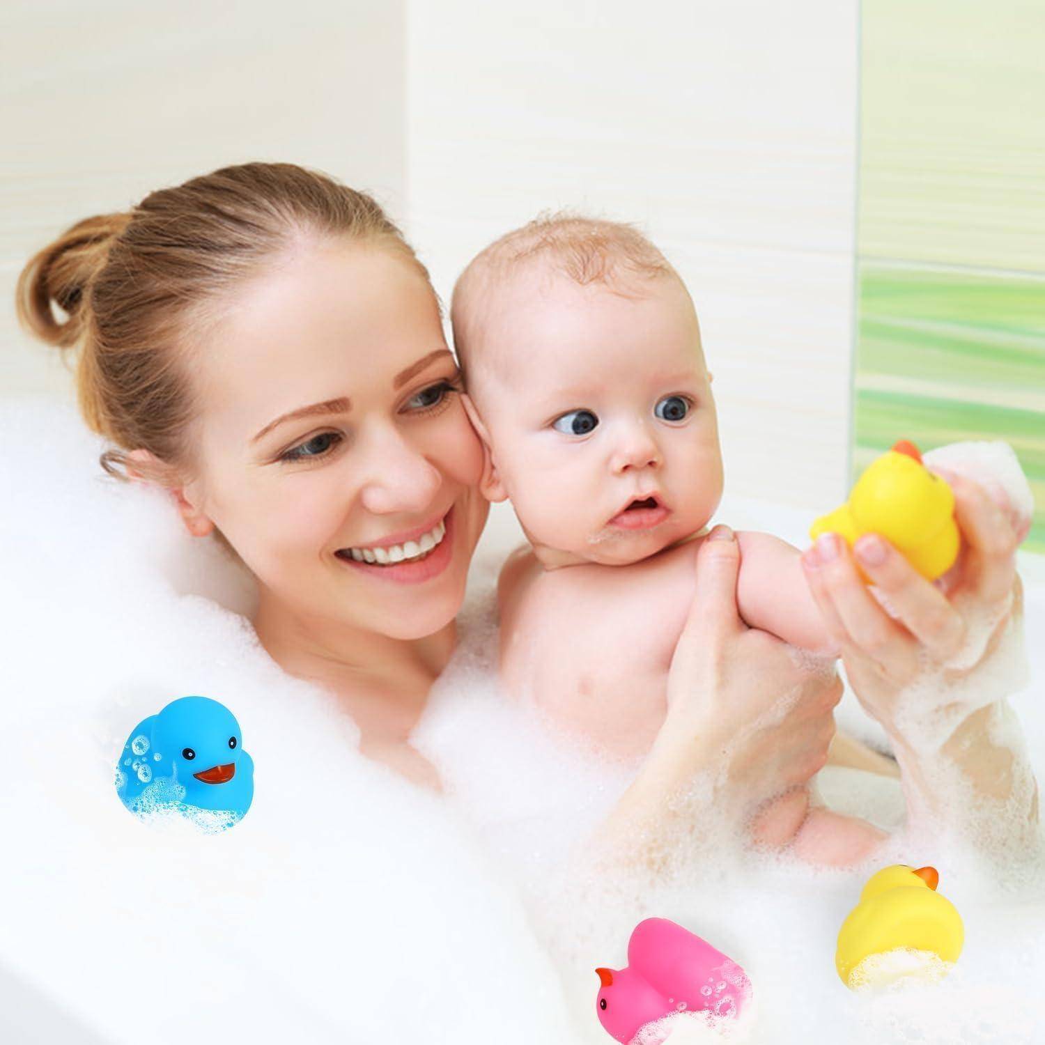 Eine Mutter und ein Baby genießen ein Bad mit bunten Gummientchen. Das Baby hält eine gelbe Ente, während blaue und rosa Enten in der Nähe schwimmen.