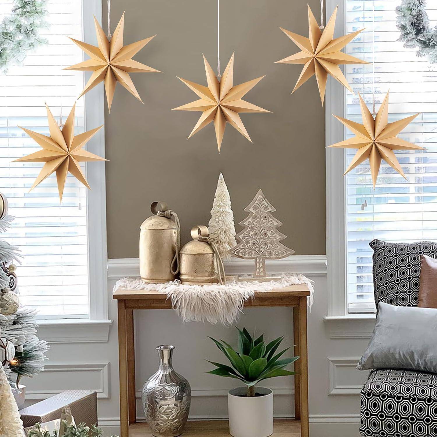 Geschmackvoll eingerichteter Raum mit hängenden 3D-Sternenornamente, einem Konsolentisch mit einem kleinen Weihnachtsbaum und metallischen Vasen sowie einer blattreichen Pflanze darunter. Die winterliche Dekoration verstärkt die gemütliche Atmosphäre.