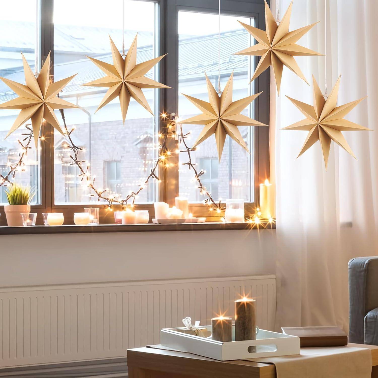 Das Bild zeigt einen gemütlichen Raum mit sternförmigen Lichtern, die am Fenster hängen. Kerzen und kleine Topfpflanzen schmücken die Fensterbank.